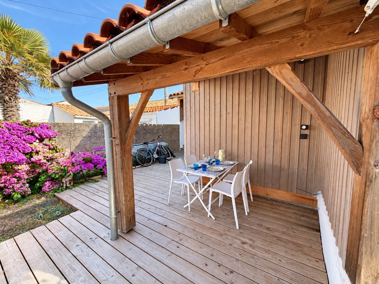 La terrasse couverte de la dépendance, table dressée sous la charpente en bois